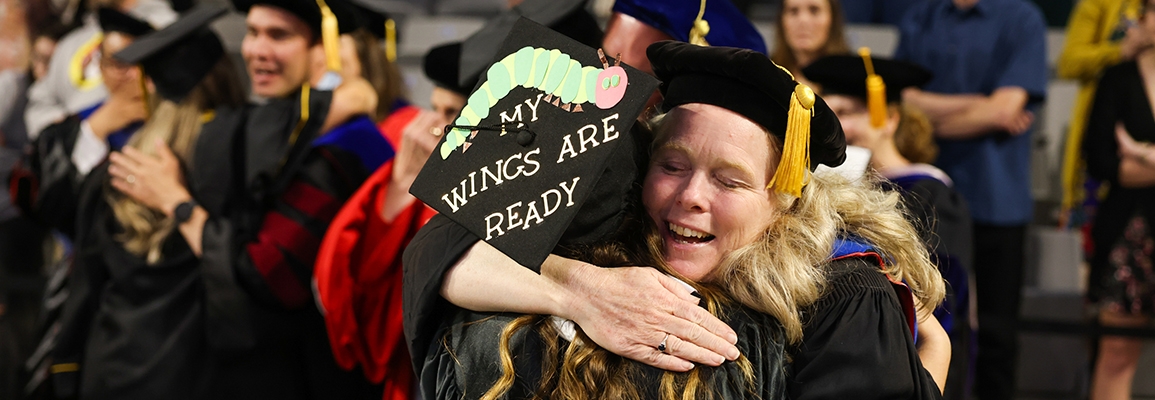 Leslie Bradbury hugs graduate at commencement ceremony
